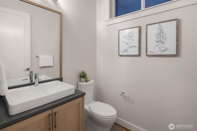 bathroom with vanity, toilet, and baseboards