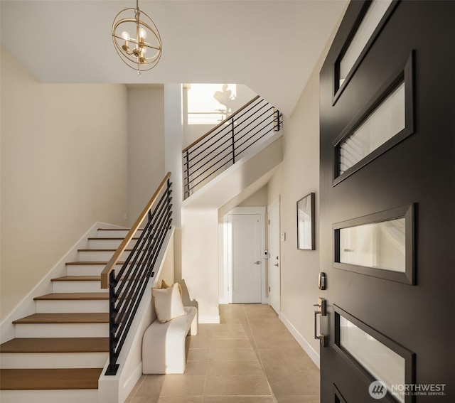 foyer featuring stairway, a high ceiling, a notable chandelier, and baseboards