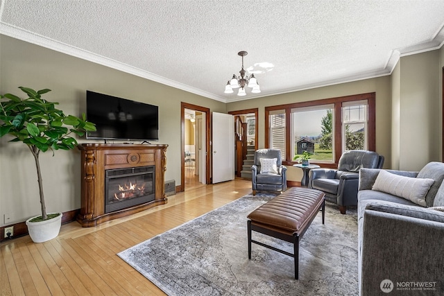 28009 SE 456th St, Enumclaw, WA 98022 - living room with light wood-style flooring, ornamental molding, a chandelier, a glass covered fireplace, and a textured ceiling