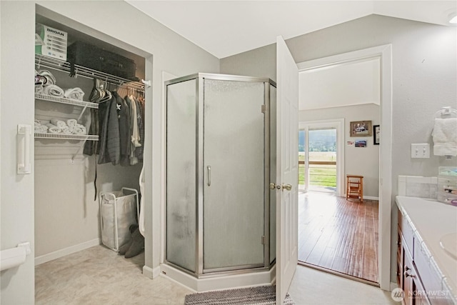 47 W Sunny Sands Rd, Cathlamet, WA 98612 - bathroom featuring vanity, a stall shower, vaulted ceiling, a spacious closet, and baseboards