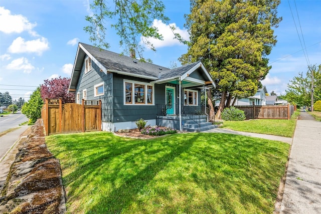 bungalow-style home with a front yard, roof with shingles, and fence