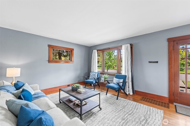 living area with visible vents, wood finished floors, and baseboards