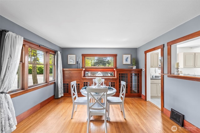 dining space featuring light wood finished floors, a healthy amount of sunlight, and visible vents