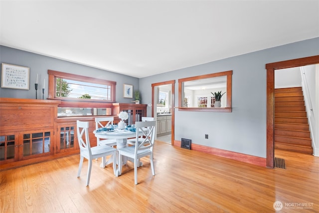 dining area featuring a wealth of natural light, stairway, visible vents, and wood finished floors