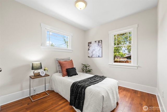 bedroom with baseboards, multiple windows, and wood finished floors
