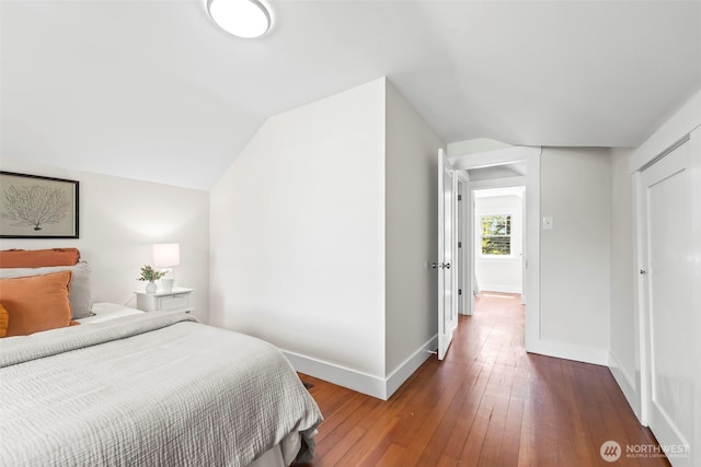 bedroom featuring baseboards, lofted ceiling, and hardwood / wood-style floors