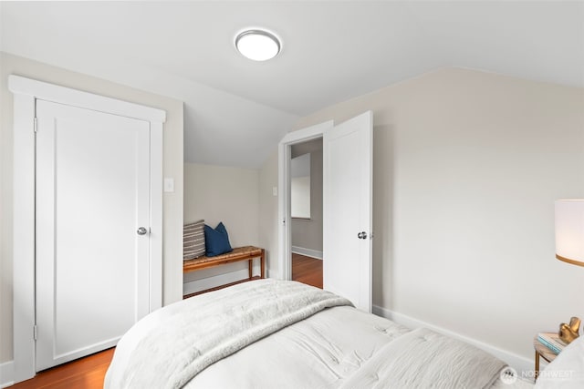 bedroom with dark wood-type flooring, baseboards, and lofted ceiling