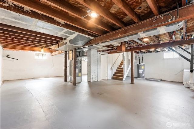 below grade area featuring electric water heater, stairway, and heating unit