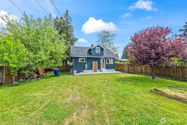 rear view of property featuring a yard, a patio area, and a fenced backyard