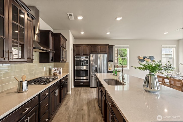 10421 12th St E, Edgewood, WA 98372 - kitchen featuring appliances with stainless steel finishes, wall chimney range hood, light countertops, dark brown cabinetry, and recessed lighting