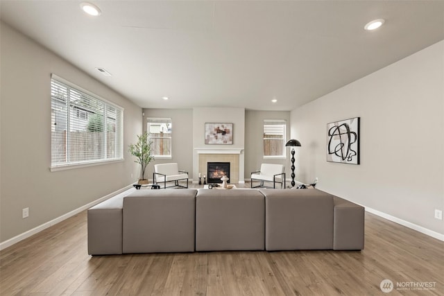 living room featuring baseboards, a fireplace, light wood finished floors, and recessed lighting