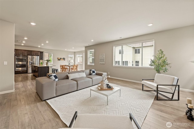 living room with recessed lighting, light wood-style flooring, and baseboards