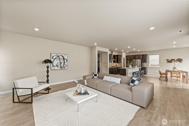 living area featuring light wood-type flooring, baseboards, and recessed lighting