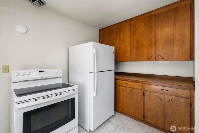 6027 S Bell St, Tacoma, WA 98408 - kitchen featuring white appliances, brown cabinetry, dark countertops, and light tile patterned flooring