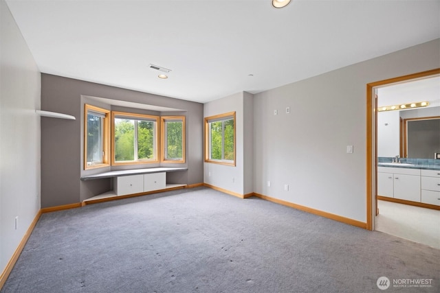 empty room with light carpet, baseboards, visible vents, and a sink