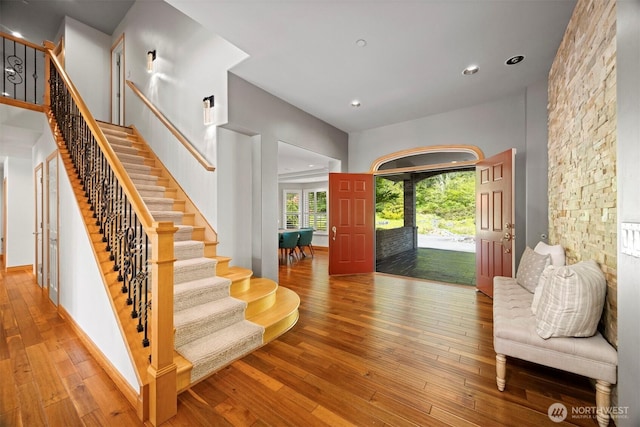 foyer entrance with stairs, wood-type flooring, a high ceiling, and recessed lighting