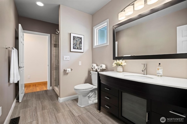 full bathroom with toilet, a stall shower, visible vents, baseboards, and vanity