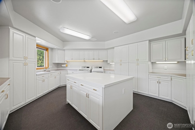 kitchen with white cabinets, washer and clothes dryer, dark carpet, and a sink