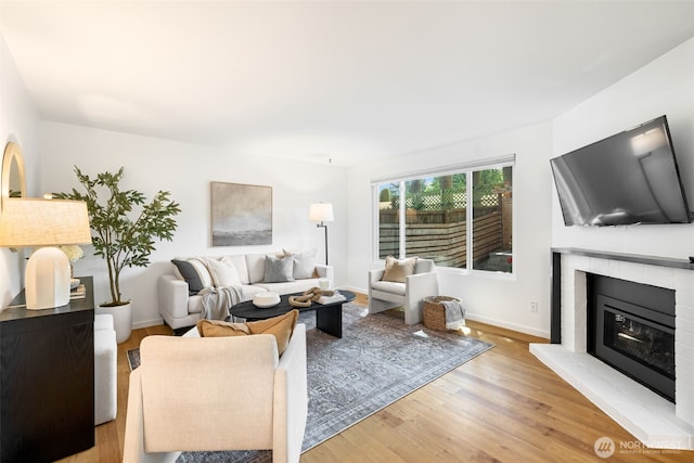 living room with wood finished floors, a fireplace, and baseboards