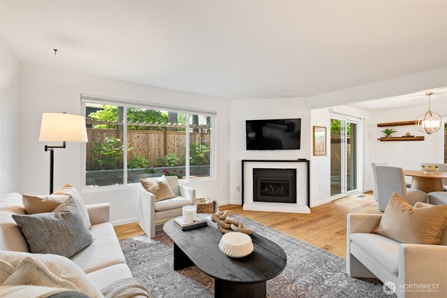 living room with healthy amount of natural light, light wood-style flooring, and a glass covered fireplace