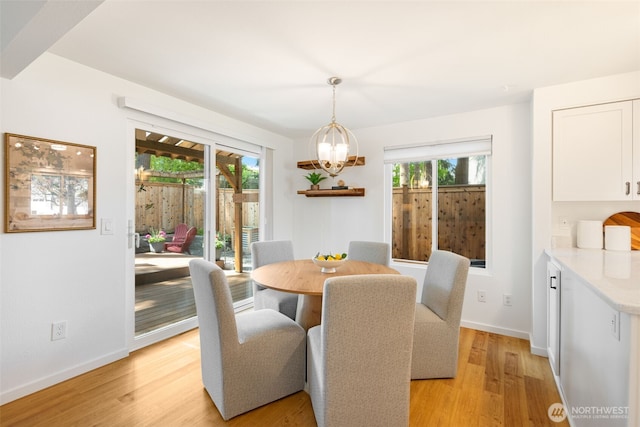 dining space featuring a chandelier, light wood-style flooring, and baseboards