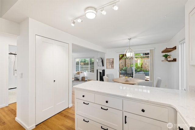 kitchen with light stone counters, light wood-style floors, healthy amount of natural light, and white cabinets