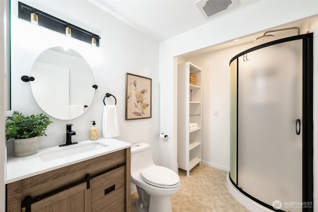 bathroom featuring a stall shower, vanity, toilet, and baseboards