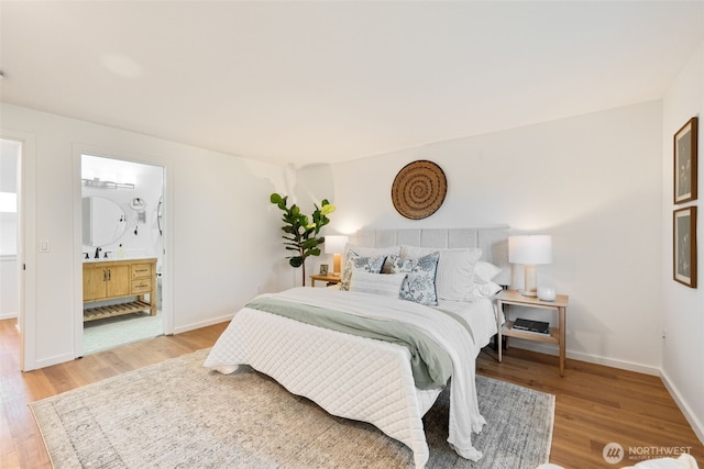 bedroom with wood finished floors, a sink, baseboards, and ensuite bathroom