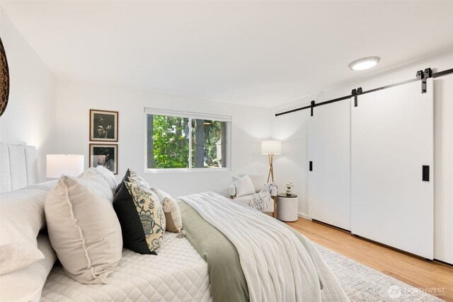 bedroom with a barn door and light wood finished floors