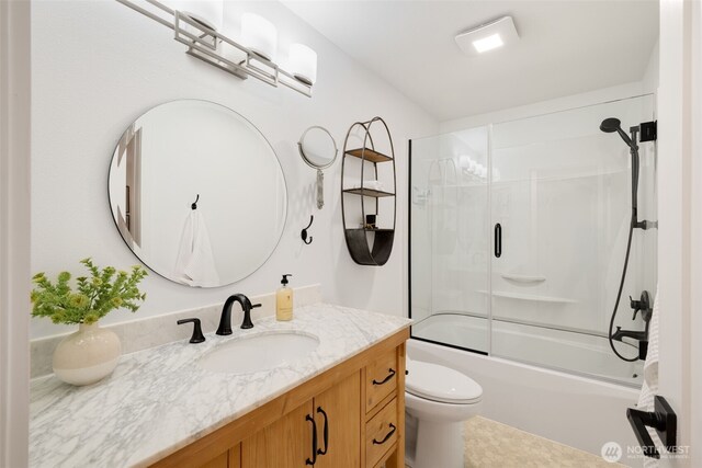 bathroom with vanity, toilet, and bath / shower combo with glass door