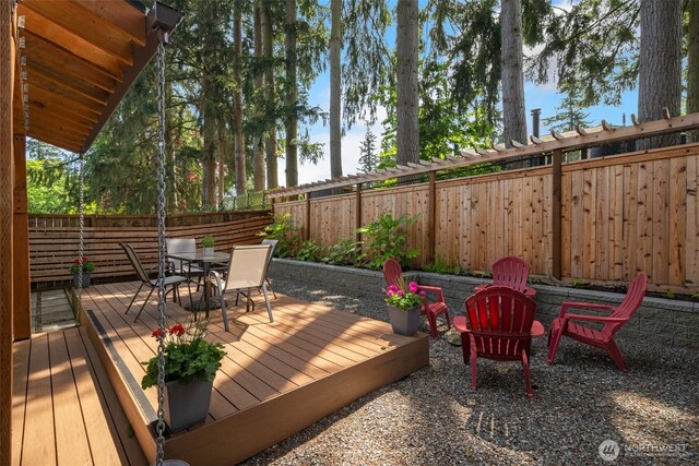 wooden terrace with outdoor dining area and a fenced backyard