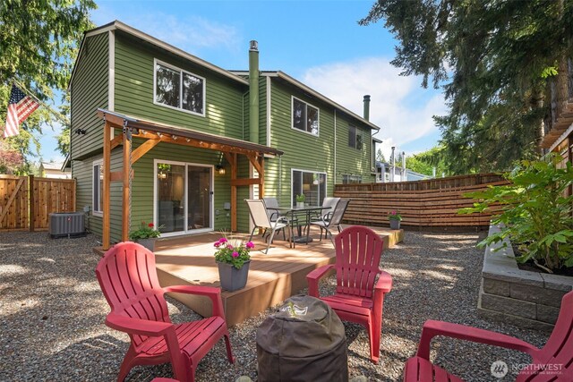 rear view of house with a fenced backyard, central AC unit, and outdoor dining space