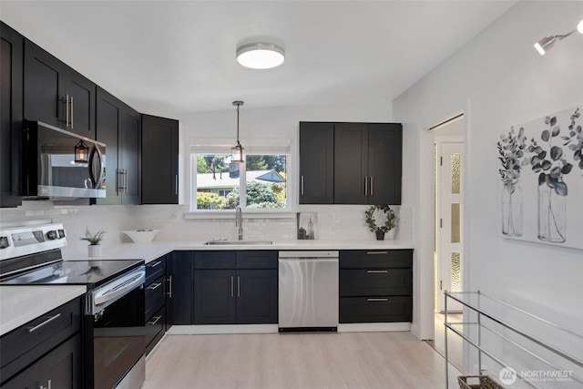 18215 3rd Pl SW, Normandy Park, WA 98166 - kitchen with appliances with stainless steel finishes, a sink, backsplash, light wood-type flooring, and light countertops