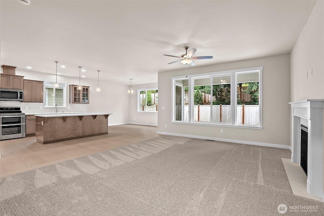unfurnished living room with light carpet, a ceiling fan, baseboards, a fireplace with flush hearth, and recessed lighting