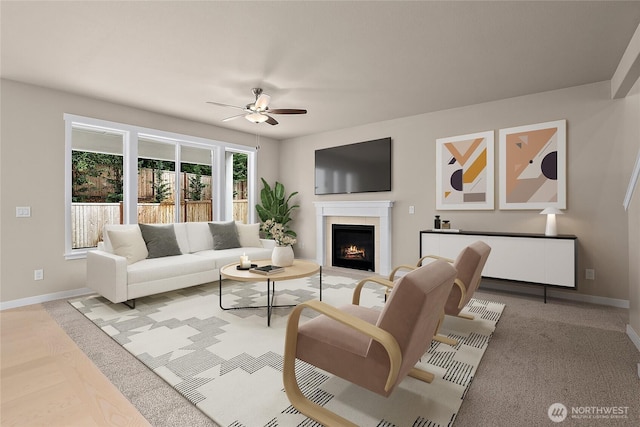 living room featuring ceiling fan, baseboards, and a tile fireplace