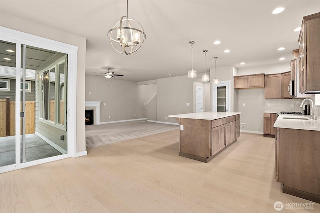 kitchen featuring light wood-type flooring, ceiling fan, recessed lighting, hanging light fixtures, and a sink