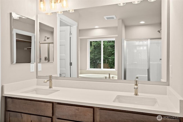 full bath with a stall shower, double vanity, a garden tub, and recessed lighting