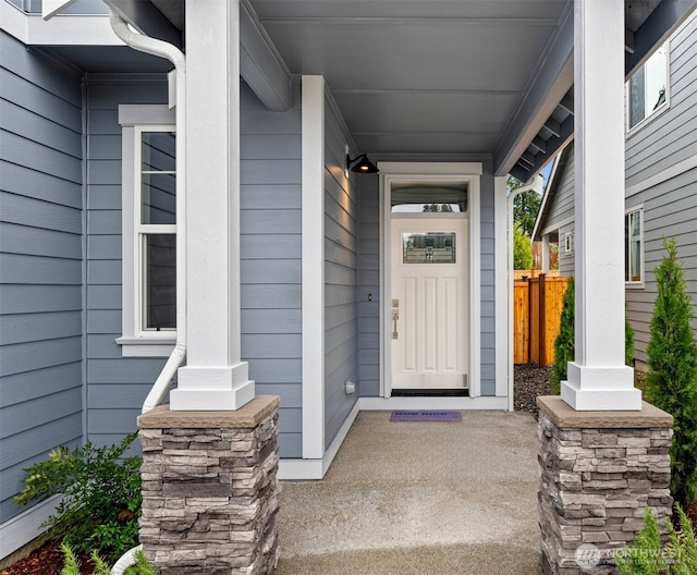 view of exterior entry featuring a porch and fence