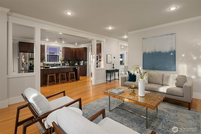 living area featuring ornamental molding, recessed lighting, light wood-style floors, and baseboards