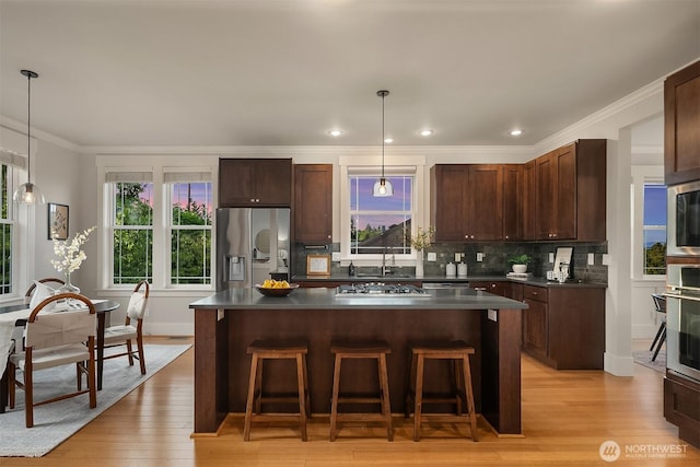 kitchen featuring appliances with stainless steel finishes, dark countertops, a breakfast bar area, ornamental molding, and a center island