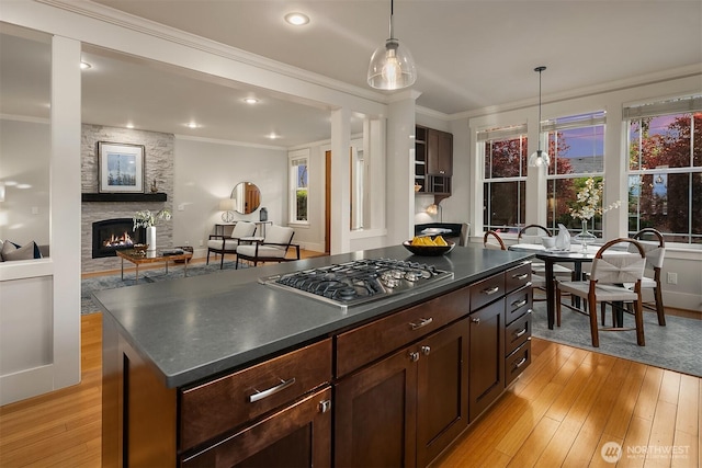 kitchen with stainless steel gas stovetop, dark countertops, light wood-style floors, ornamental molding, and recessed lighting