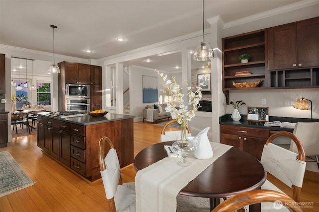 kitchen with stainless steel appliances, dark countertops, crown molding, light wood-style flooring, and a center island
