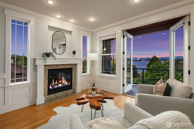 living room featuring ornamental molding, a premium fireplace, wood finished floors, plenty of natural light, and recessed lighting