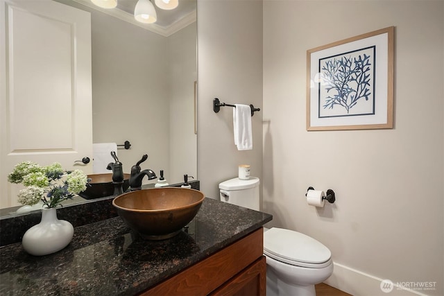 bathroom with ornamental molding, toilet, and vanity
