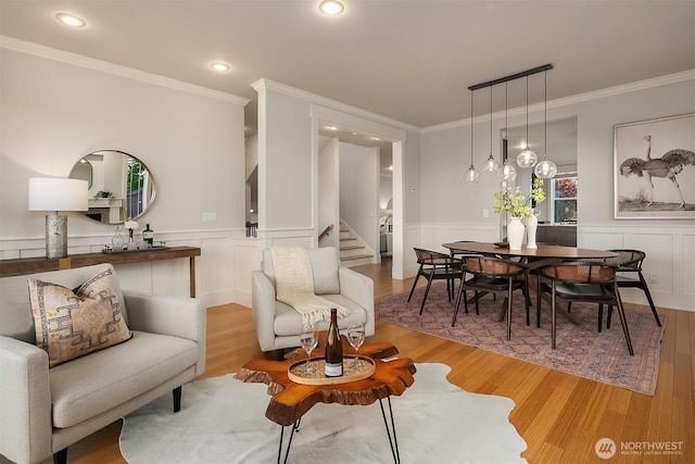 living room with light wood-style flooring, ornamental molding, wainscoting, stairs, and recessed lighting