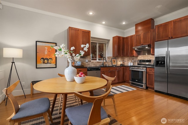kitchen with stainless steel appliances, under cabinet range hood, a sink, dark countertops, and backsplash