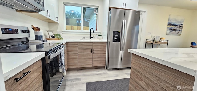 1442 E 31st St, Tacoma, WA 98404 - kitchen with brown cabinets, a sink, light wood-style flooring, stainless steel appliances, and modern cabinets