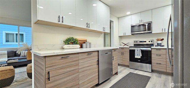 1442 E 31st St, Tacoma, WA 98404 - kitchen featuring modern cabinets, stainless steel appliances, light wood-style flooring, and white cabinets