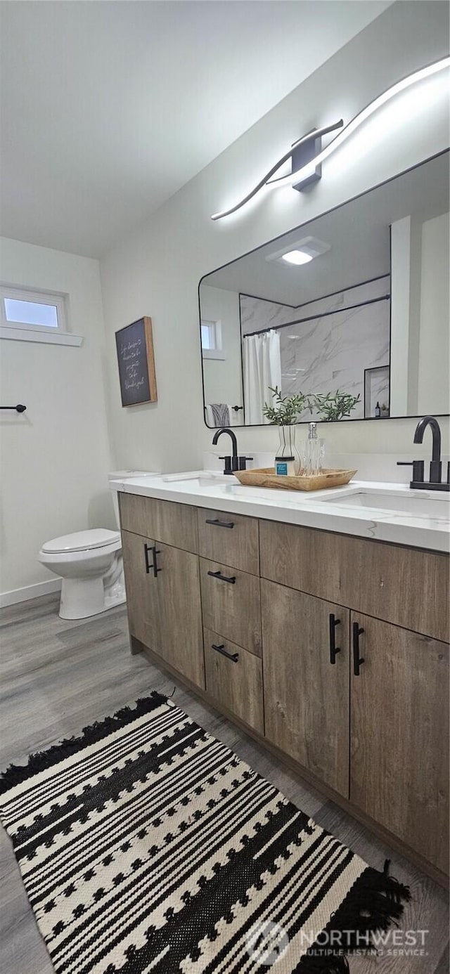 1442 E 31st St, Tacoma, WA 98404 - bathroom featuring double vanity, wood finished floors, toilet, baseboards, and a sink