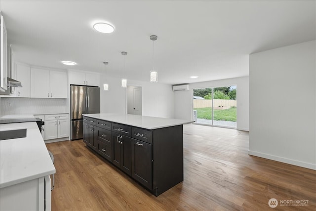 kitchen featuring freestanding refrigerator, an AC wall unit, white cabinetry, and light countertops